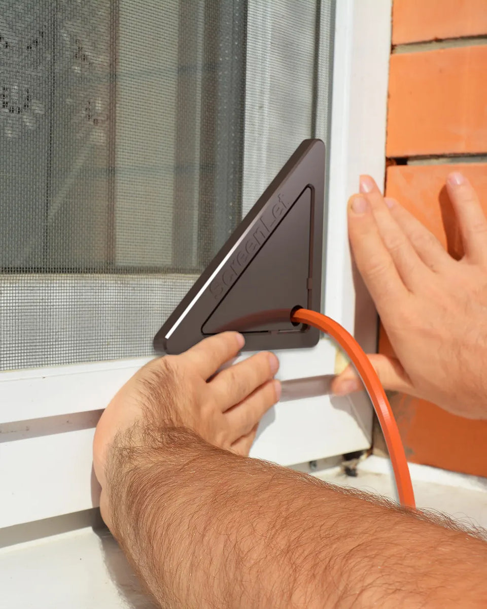 Hands installing ScreenLet on a window, seamlessly passing an orange cable through the screen.