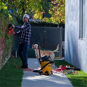 Man using power tools in the backyard with ScreenLet, alongside a playful dog